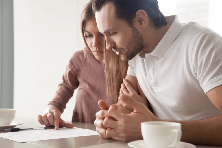 A couple sitting at a table, looking at a document together.