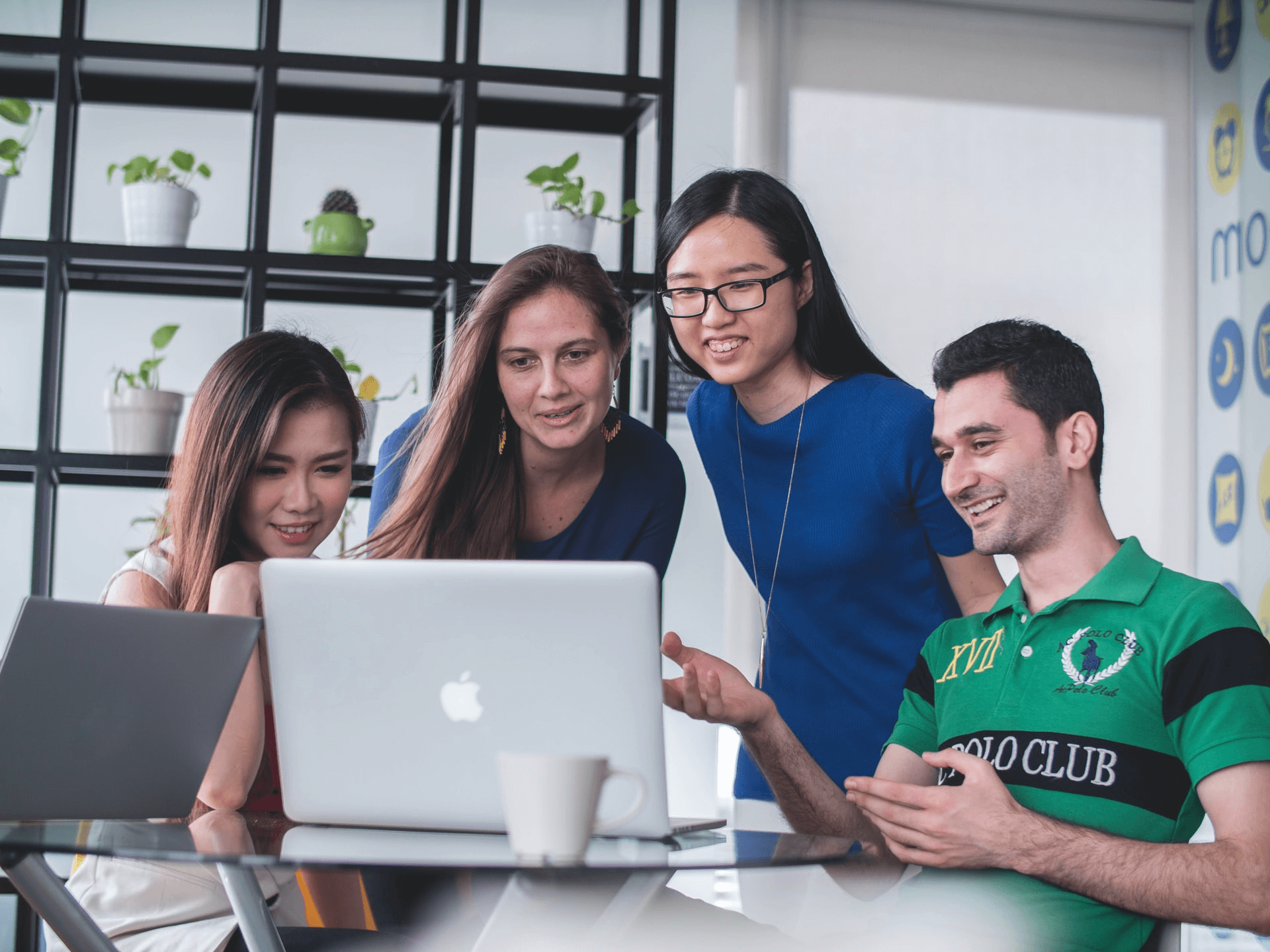 Image of four colleagues in front of a laptop